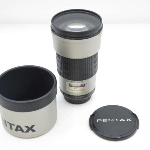 Lens with Pentax branding, lens hood, and cover on a white surface.