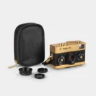 A Rollei 35 camera with a gold and black finish, accompanied by a black carrying case and three camera accessories, laid out on a plain background.