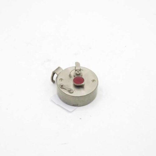 A small metal object with a circular shape, featuring a red circular button on top and a small hooked lever.