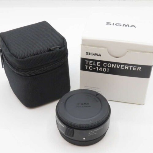 Sigma TC-1401 tele converter with its black carrying case and original packaging box on a white background.