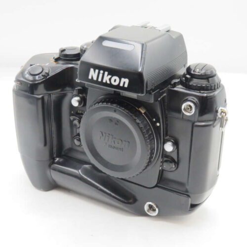 A vintage Nikon film camera with a prominent viewfinder and various control dials, featuring a lens cap marked 'Nikon F mount.'