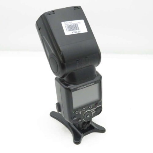 A Nikon Speedlight SB-910 camera flash with a barcode label and price tag on the flash head, mounted on a stand, against a white background.