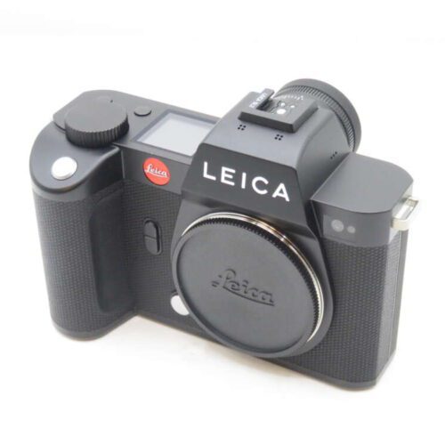 A black Leica digital camera with a simple design, featuring a detachable lens cap and textured grip.