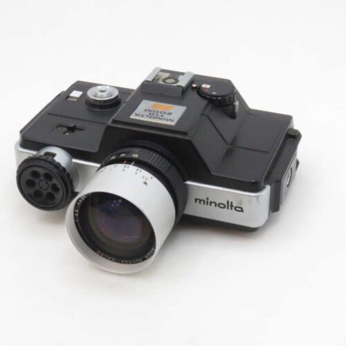 A vintage Minolta Minoltina-P 8mm movie camera with a black and silver body, featuring a prominent lens and dials for adjustments, set against a plain white background.