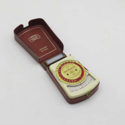 A vintage Zeiss Ikon exposure meter in a brown leather case, featuring a circular dial labeled "Ikophot" and various exposure settings, with "Stuttgart, Germany" printed inside the case lid.