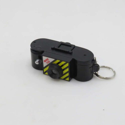 A small black mini camera keychain with yellow and black striped detailing, featuring the label 'MINI 110'.