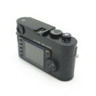 A black Leica digital camera viewed from the back, showing the LCD screen, control buttons, and dials.