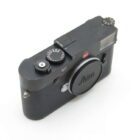 A Leica M9 digital camera with a black body, featuring a prominent red Leica logo and a lens cap.