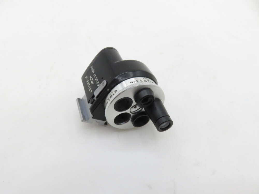A black and silver optical instrument with multiple lenses, featuring a cylindrical body and a protruding lens on a white background.