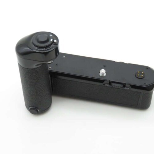A black camera battery grip with a textured handle and control dial on a white background.