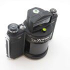 A vintage panoramic film camera with a rotating lens, black in colour, featuring knobs and levers for adjustments, branded with "Widelux" and "Super Wide Angle" on its cylindrical body.
