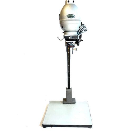 A vintage Johnson outboard motor with a metal pole, mounted on a display stand, showcasing its distinctive oval-shaped engine cover and attachments for boat mounting.