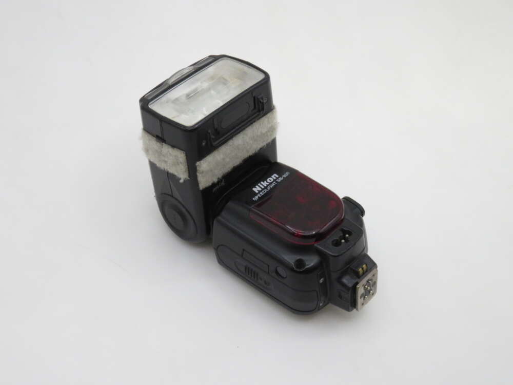 IMG_1146 A Nikon SB-800 Speedlight flash unit with a red infrared filter and Velcro strap for attachment, set against a plain white background.