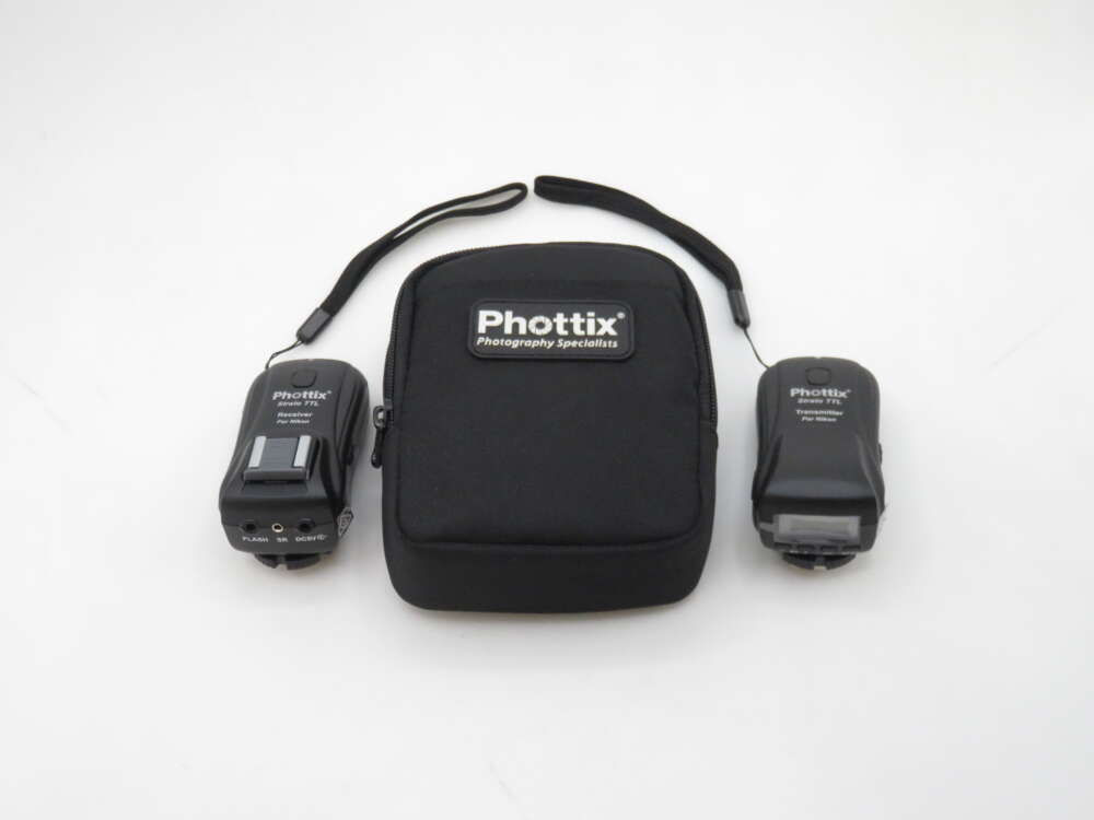 IMG_1164 A Phottix wireless flash trigger set including a black zippered carrying pouch labeled 'Phottix Photography Specialists', with a flash receiver and transmitter placed on either side.