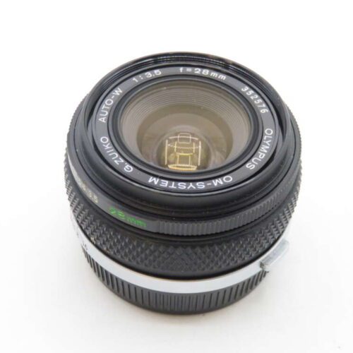 A close-up view of an Olympus OM-System Zuiko Auto-W 28mm f/3.5 camera lens, showing the front element and engraved details including the lens model and specifications.