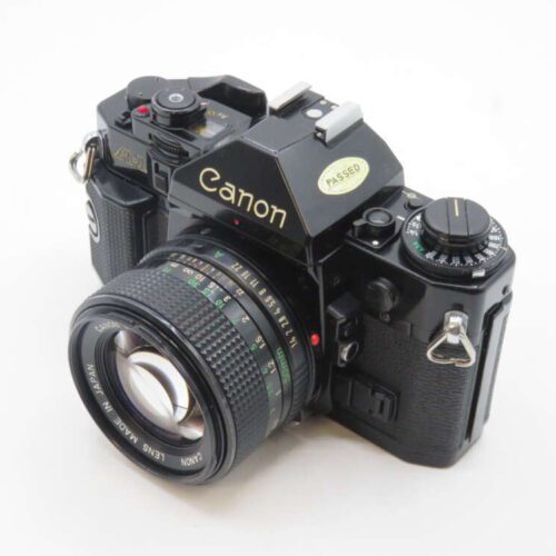 A vintage Canon film camera with a black body and textured grip, featuring multiple control dials and a Canon lens attached.