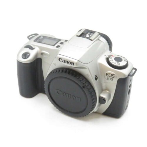 Canon EOS 300 film camera with a silver body and a black grip, featuring a lens cap on, mode dial, and LCD screen on top.