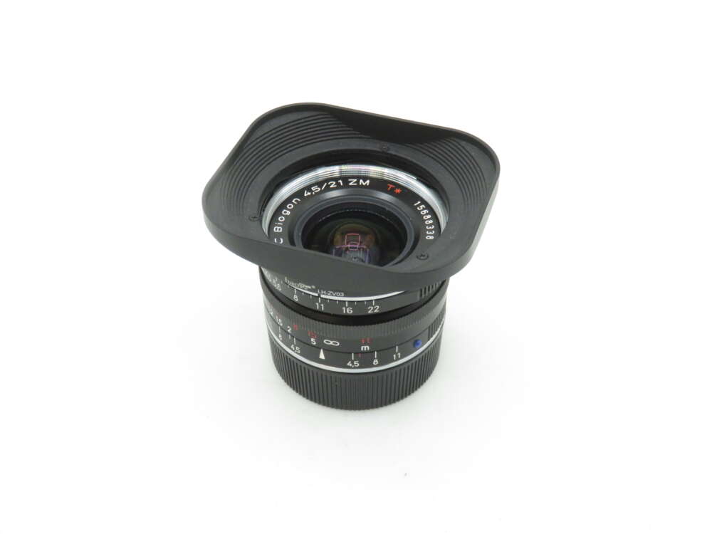 IMG_1522 A black camera lens with a wide angle hood, featuring engraved markings and the text 'Biogon 4.5/21 ZM T*.'