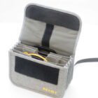 A grey fabric filter case with multiple compartments, showcasing several circular camera filters inside, with a branded logo visible on the front.