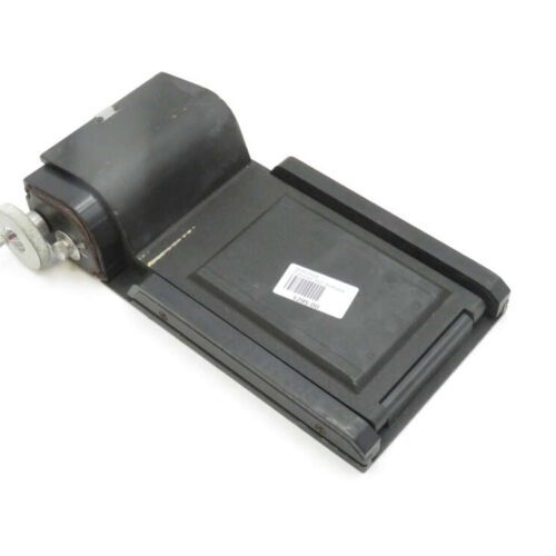 A vintage black slide projector with a metal knob and handle, resting on a white background with a barcode sticker on its surface.