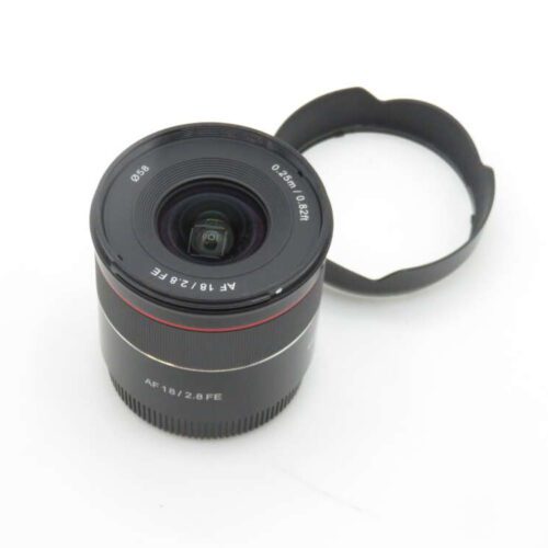 A camera lens with the label 'AF 18/2.8 FE' positioned next to a lens hood on a plain white background.