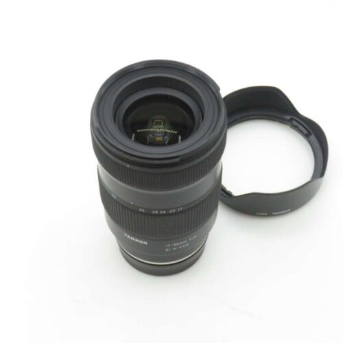 A Tamron 17-28mm f/2.8 Di III RXD camera lens with a detached lens hood on a white background.