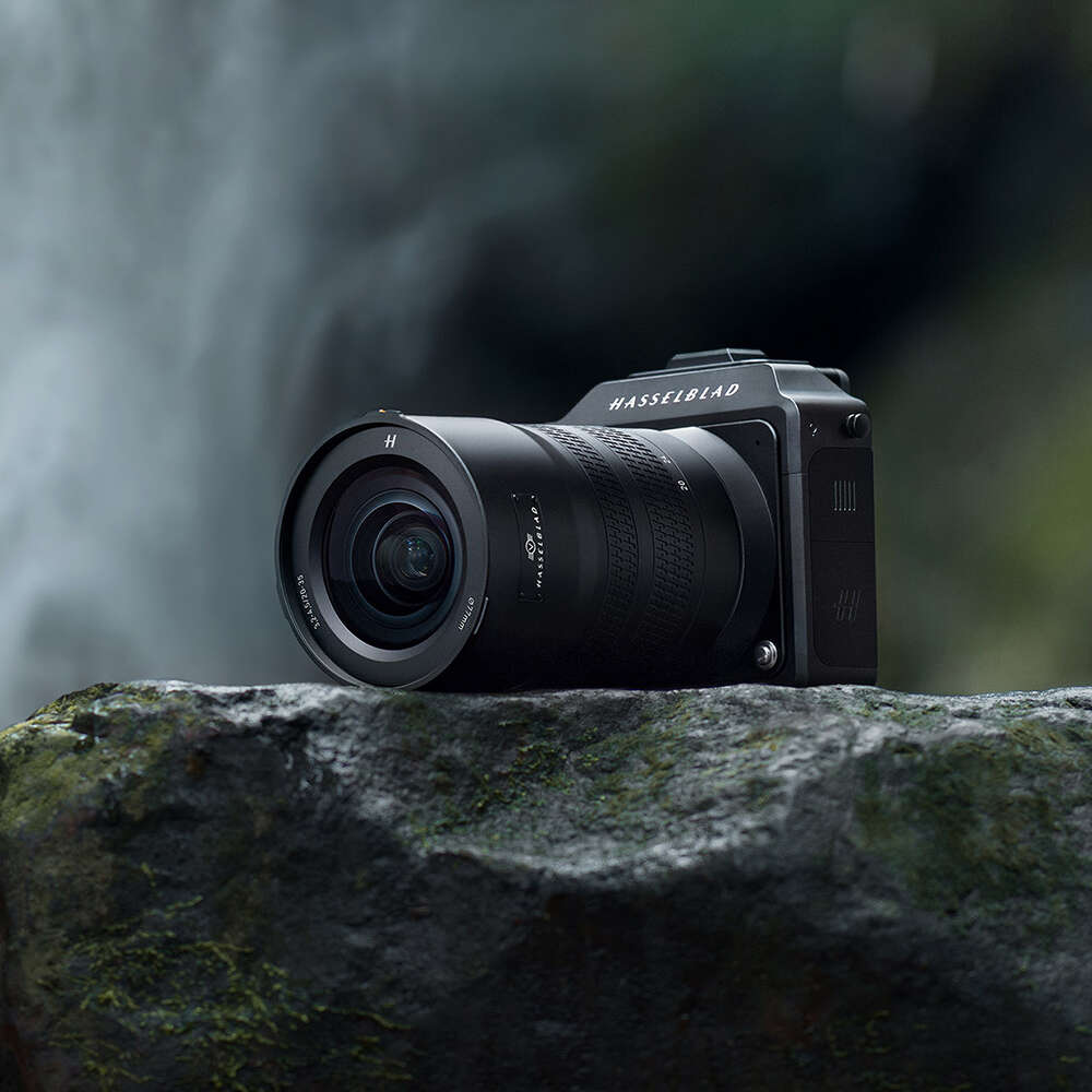 Hasselblad cameras resting on a moss-covered rock, with a blurred outdoor background.