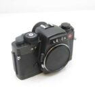 A Leica R7 film camera with a black body and a silver lens cap, showing dials and control buttons on the top.