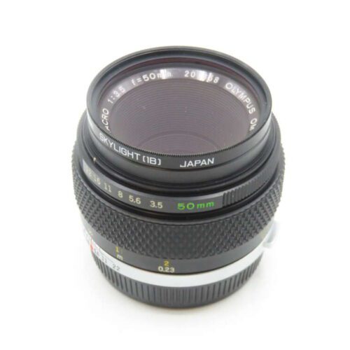 An Olympus OM-System Zuiko Auto-Macro 50mm lens with a Skylight filter attached, featuring f-stops from 3.5 to 16, and made in Japan. The lens has a textured focus ring and distance markings in meters and feet.