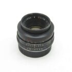 A Leica Summicron-R 50mm f/2 camera lens with focus and aperture rings visible against a plain white background.