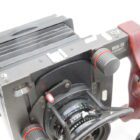 Close-up of a Cambo Wide DS large format camera, featuring a black and red handle, bellows, and lens with control dials.