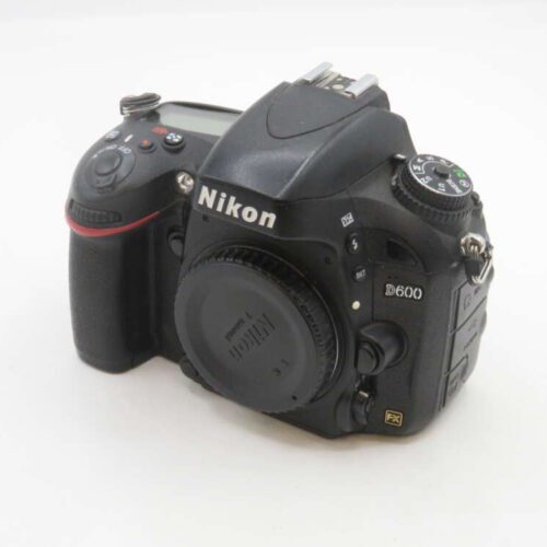 A Nikon D600 DSLR camera body with a lens cap on a white background, featuring various control dials and buttons.