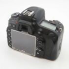 A Nikon DSLR camera viewed from the back, showing its LCD screen, control buttons, and viewfinder. The camera is black and features a control dial and buttons for menu, delete, and playback on the left side.