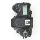 Top view of a DSLR camera showing the mode dial, an LCD screen, and various control buttons.