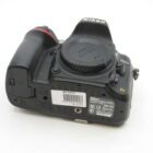 A Nikon D500 DSLR camera with a body cap attached, viewed from a slightly elevated angle showing the top and bottom parts of the camera, including various labels and a barcode sticker on the bottom plate.