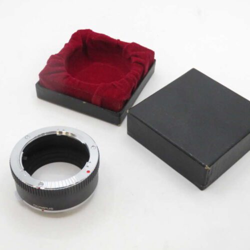 A camera lens adapter ring placed next to its black box with a red velvet interior lining.