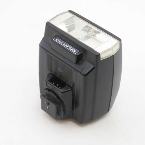 A black Olympus camera flash unit with a transparent front cover and a branded label on top, shown against a plain white background.