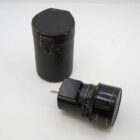 A vintage camera lens with a cap is lying next to a cylindrical black leather case with a lid, placed on a white surface.