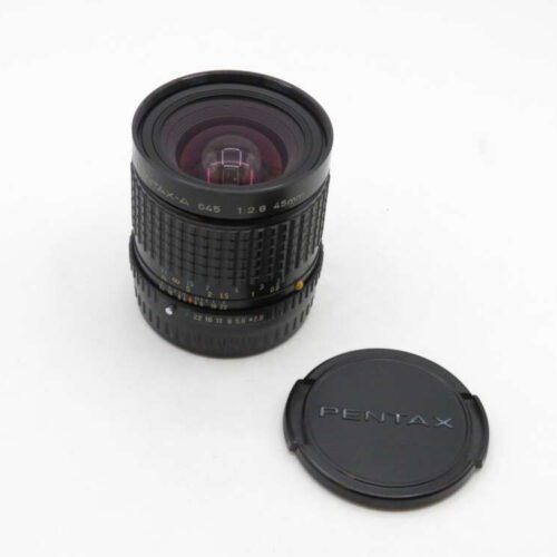 Pentax-A 645 45mm f/2.8 lens with its cap placed beside it on a white surface.
