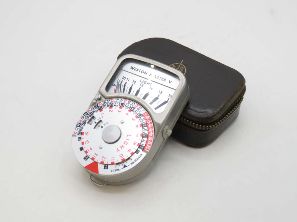 IMG_2308 A vintage Weston Master V light meter with a circular dial, placed on a small brown zippered case.