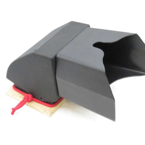 A black padded archery arm guard with a red cord attached, resting on a wooden surface.