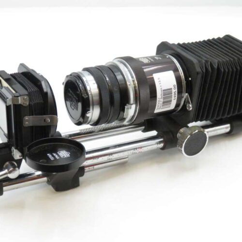 A bellows camera setup with an adjustable lens and slide holder mounted on metal rails, used for close-up photography.