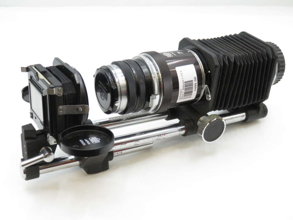 IMG_2324 A bellows camera setup with an adjustable lens and slide holder mounted on metal rails, used for close-up photography.