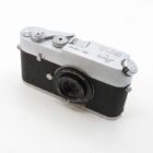 A vintage Leica camera featuring a black textured body with silver metal components and a Funleader lens attached, positioned on a plain white surface.