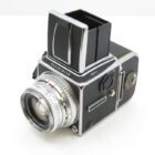 A vintage Hasselblad 500 C/M camera with a large viewfinder and silver lens, shown against a plain background.