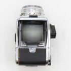 A vintage silver and black reflex camera viewed from above, showing its viewfinder and lens settings.