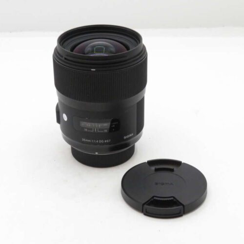 A black Sigma 35mm camera lens with its cap placed next to it on a white surface.
