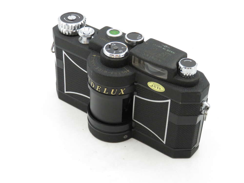 IMG_3092 A vintage Widelux camera with a black body and silver dials, showcasing a distinctive rounded lens design.