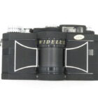 A black Widelux film camera with a distinctive cylindrical lens and silver detailing.