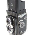 A vintage Yashica-Mat twin-lens reflex camera with a side knob and open viewfinder.